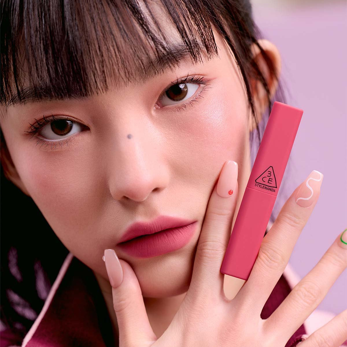 3CE Sketch Stick 8 shades : maquillage yeux/visage, femme en gros plan tenant le stick rose, ambiance beauté studio