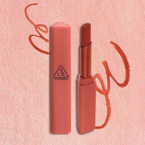 Décris l'image : 3CE Sketch Stick 8 shades de 3CE, crayons lèvres sur fond rose avec inscriptions rouges, maquillage.