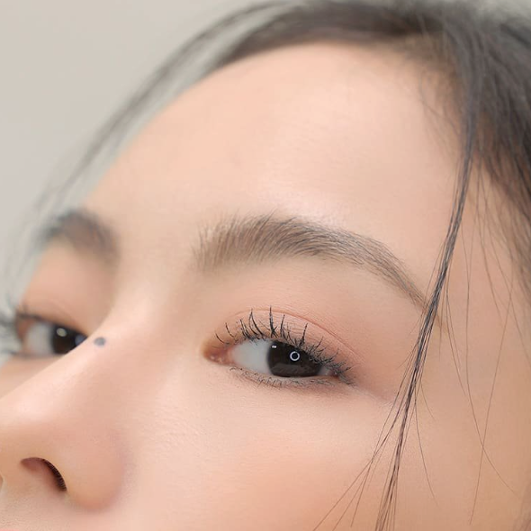 Décris l'image en français : 3CE Super Slim Waterproof Mascara, gros plan sur les cils, maquillage waterproof, marque 3CE.