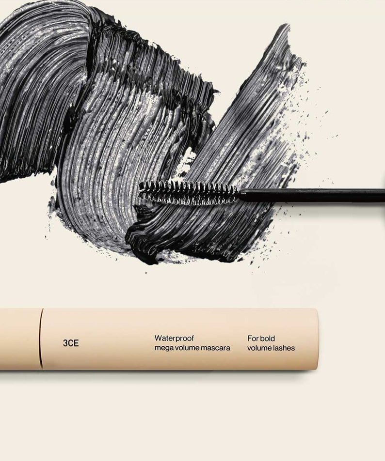 3CE Waterproof Mega Volume Mascara, gros plan tube et brosse sur maquillage noir, contexte beauté, étiquette 3CE visible