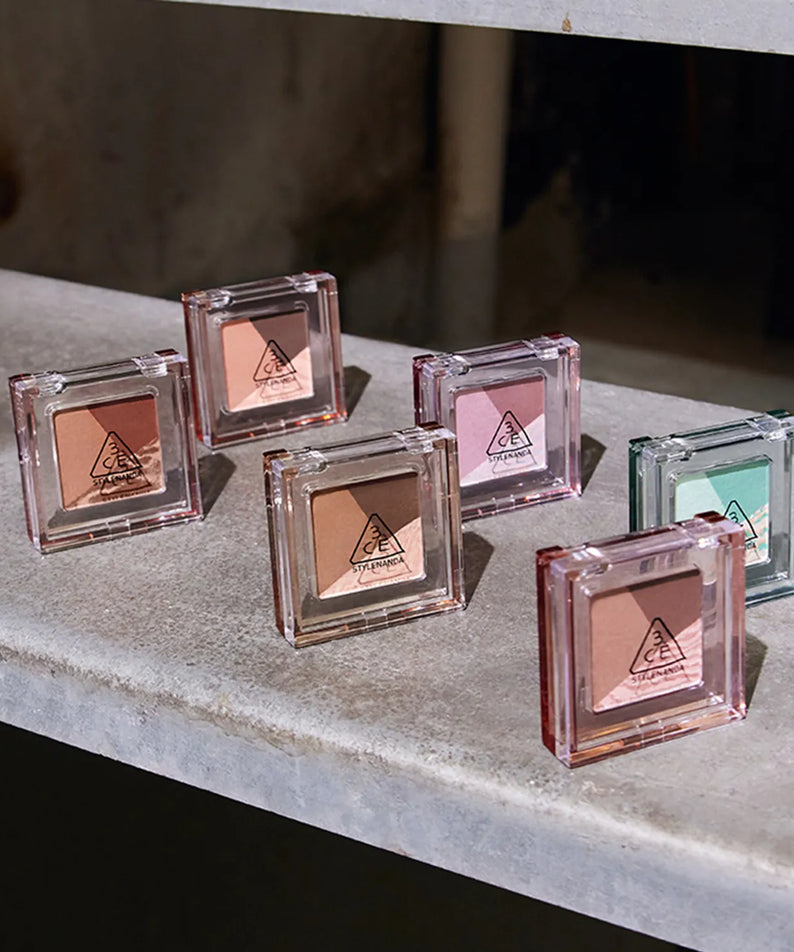 Palette d'ombres à paupières 3CE Color Grid Eyeshadow exposée sur une surface grise élégante, parfaite pour un look maquillage créatif.