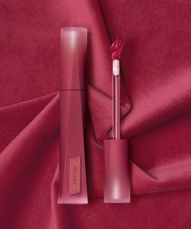 Rouge à lèvres 3CE Velvet Lip Tint Plush sur fond de velours rouge, offrant une finition douce et luxueuse.
