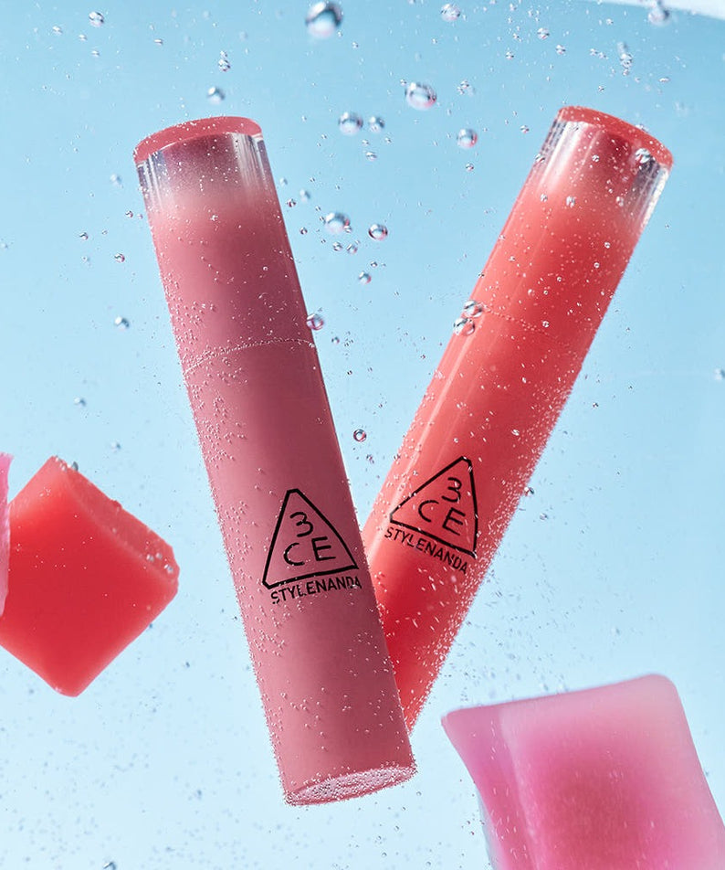 Rouges à lèvres "3CE Lazy Pop Lip Stain" flotte dans l'eau bleue, montrant les détails du produit et sa couleur vive.