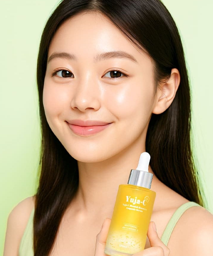 Femme souriante tenant un flacon de 3W CLINIC Yuja C Blemish Recovery Ampoule Serum 100ml devant un fond vert pastel.