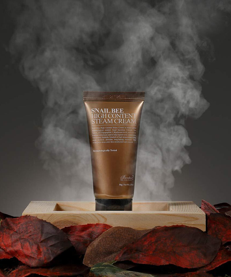 BENTON Snail Bee High Content Steam Cream 50g de la marque BENTON, tube crème sur plateau, vapeur visible, fond sombre.