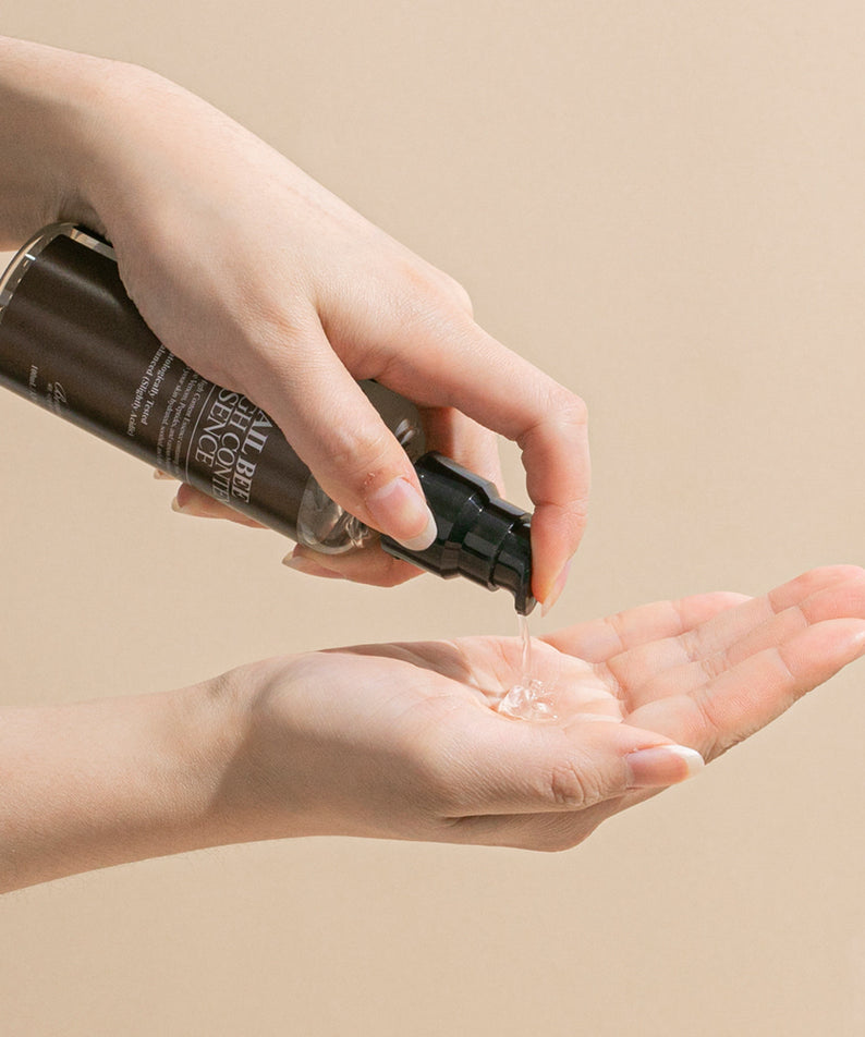 Décrivez l’image : BENTON Snail Bee High Content Essence 100ml, la main applique le sérum sur la peau, fond beige, marque BENTON.