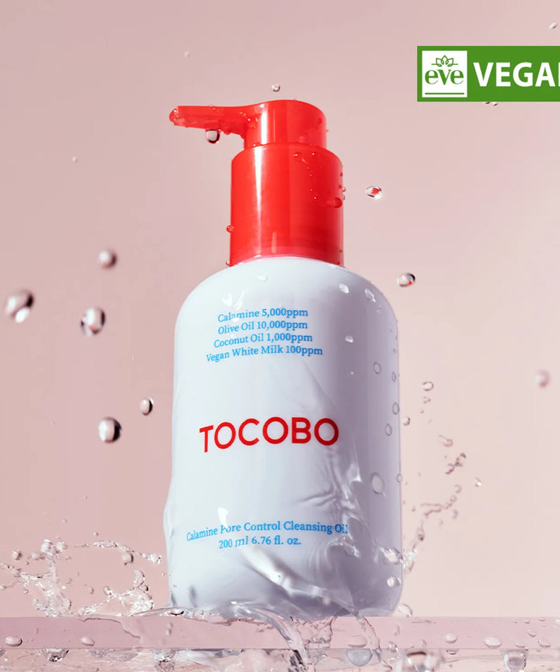TOCOBO Calamine Pore Control Cleansing Oil 200ml, flacon rouge sur fond rose avec éclaboussures d’eau, contexte soin visage.