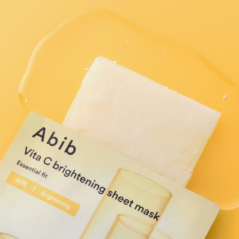 ABIB Essential Fit Vita C Brightening Sheet Mask d’Abib, masque en tissu sur fond jaune, packaging visible, vue rapprochée.