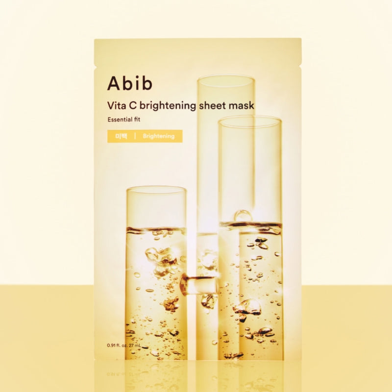 ABIB Essential Fit Vita C Brightening Sheet Mask, pack crème et flacons dorés, gouttes jaunes sur fond clair.