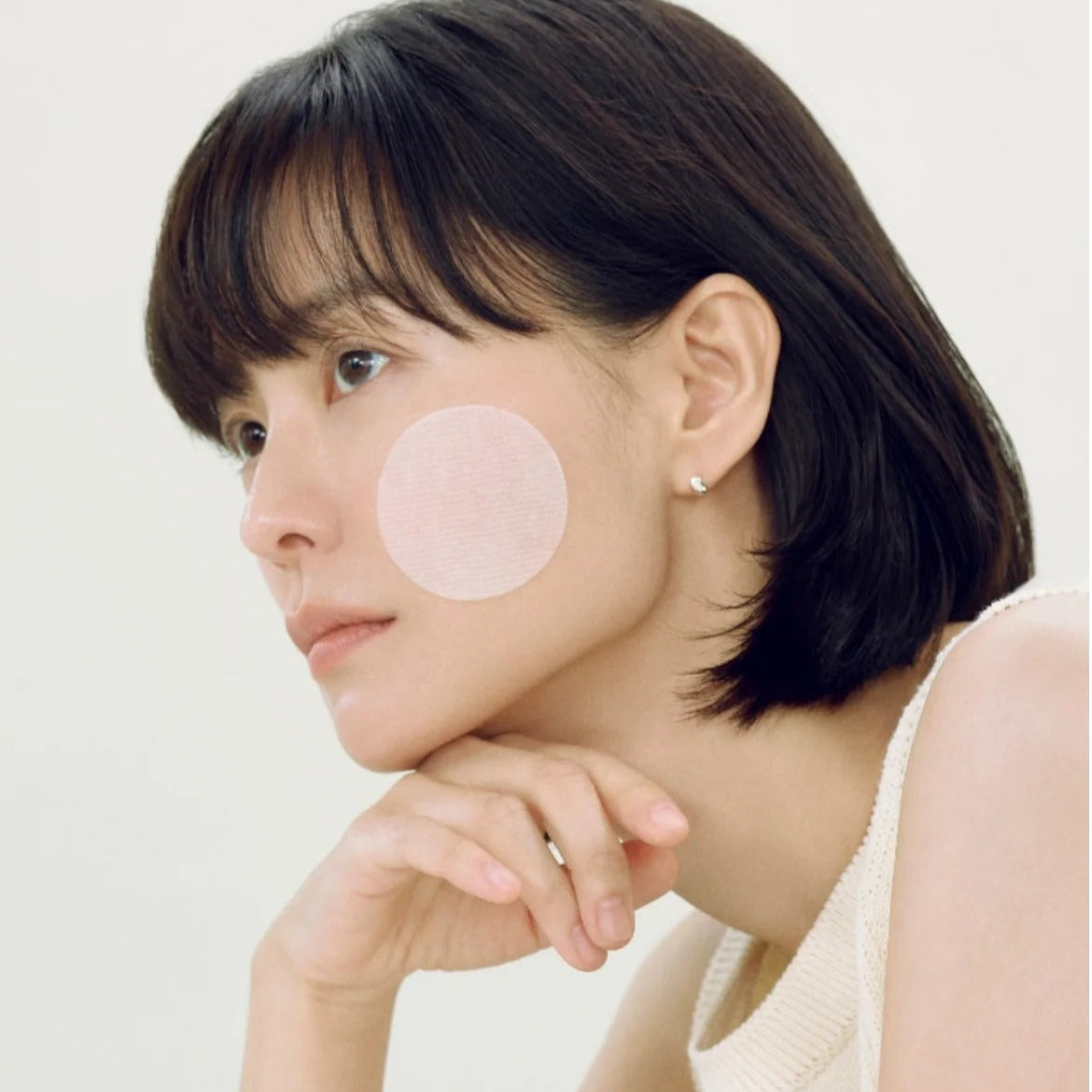 ABIB Heartleaf Spot Pad Calming Touch 70 pads de ABIB, visage féminin avec patch apaisant rond sur la joue, fond clair.