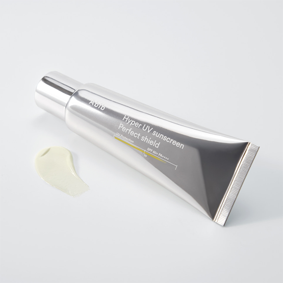 Décris l'image en français : ABIB  Hyper UV Sunscreen Perfect Shield 50ml, tube argent et crème, fond blanc, vue produit.