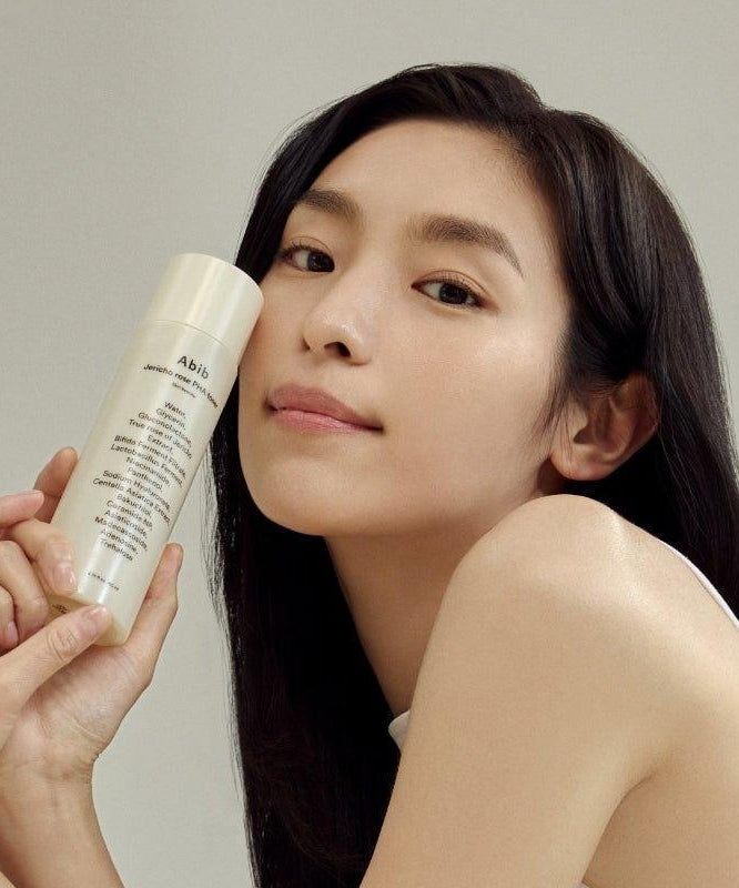 ABIB Jericho Rose PHA Toner Skin Booster 200ml : femme l’application du toner, flacon beige sur fond clair.