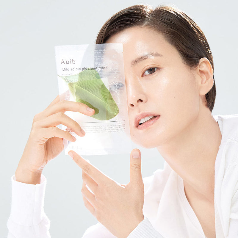 ABIB Mild Acidic pH Sheet Mask 30ml : femme appliquant un masque feuille sur le visage, emballage ABIB en arrière-plan