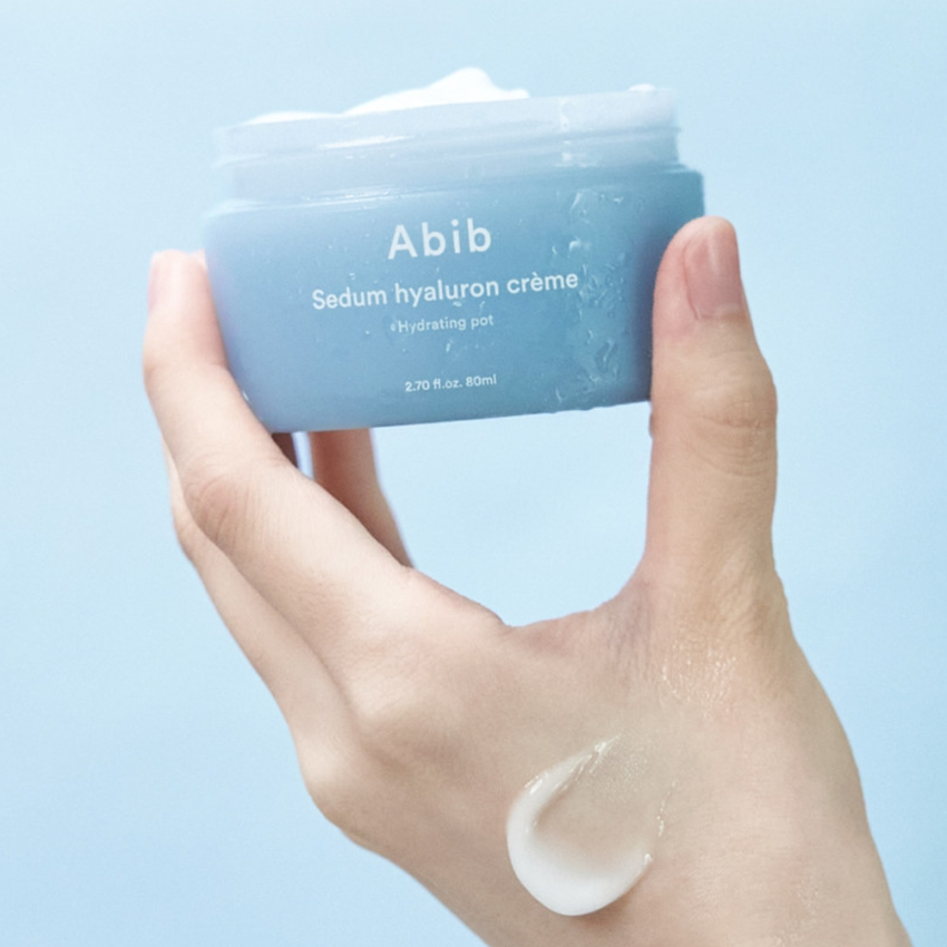 ABIB Sedum Hyaluron Creme Hyadrating Pot 80ml, mains tenant le pot bleu, crème hydratante sur fond clair