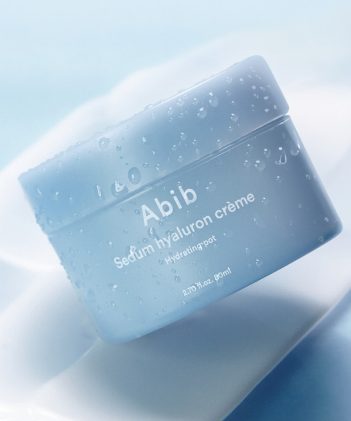 Décris l'image en français : ABIB Sedum Hyaluron Creme Hyadrating Pot 80ml, pot bleu sur fond clair avec gouttelettes.