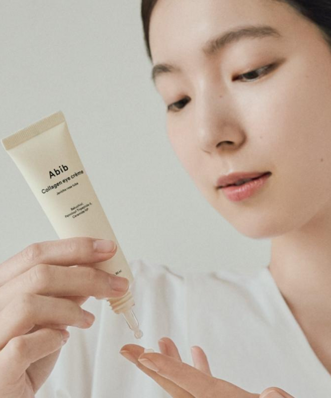 Femme appliquant ABIB Collagen Eye Cream Resurrection Herb Tube 30ml sur ses doigts.