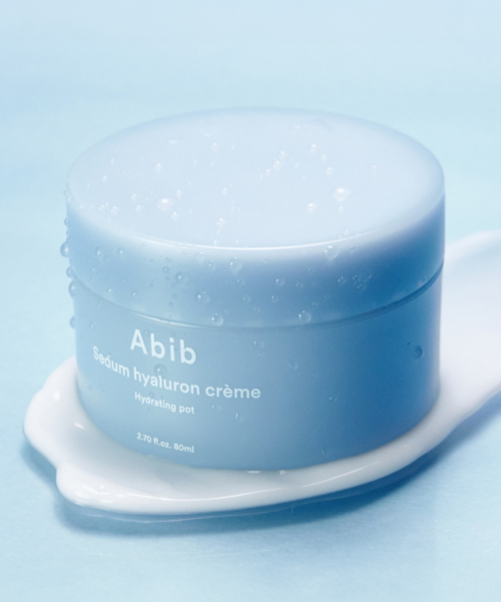 Pot de crème ABIB Sedum Hyaluron Creme Hyadrating Pot 80ml sur fond bleu, crème hydratante visible autour du pot.