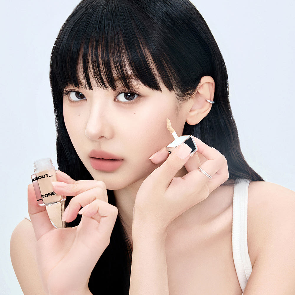 ABOUT TONE  Skin Layer Cover Fit Concealer 5.6g, marque ABOUT TONE, maquillage sur fond clair, femme applique le correcteur