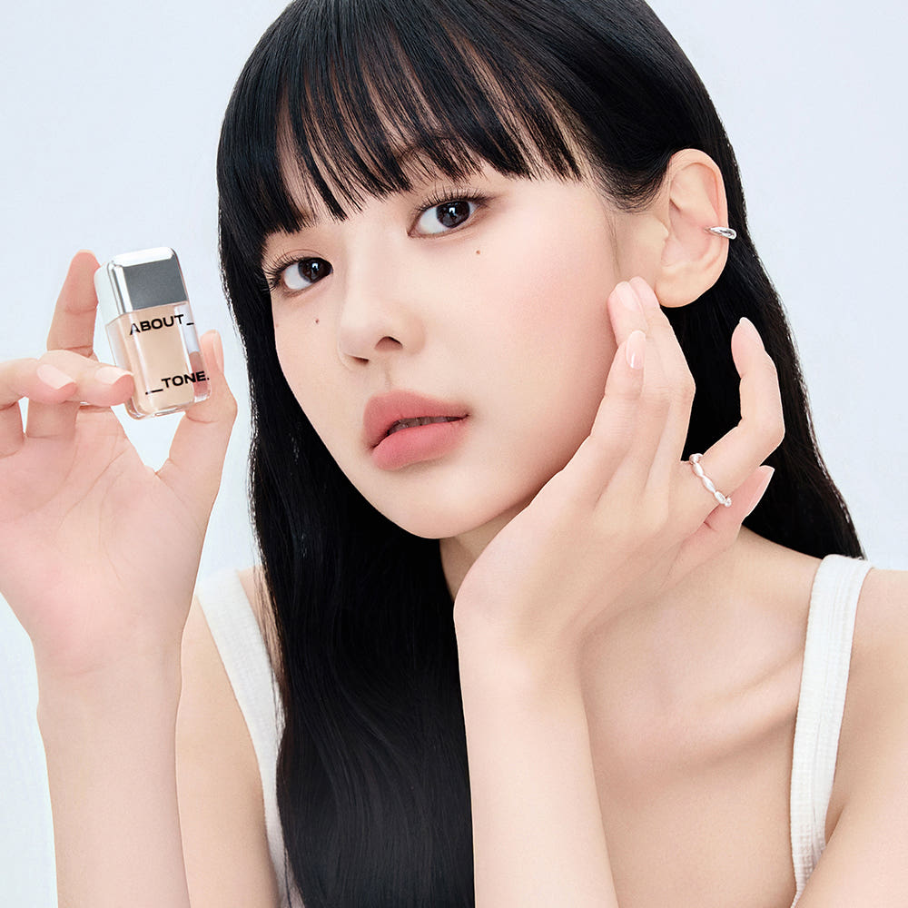 ABOUT TONE  Skin Layer Cover Fit Concealer 5.6g, jeune femme applique le correcteur, produit et marque en gros plan