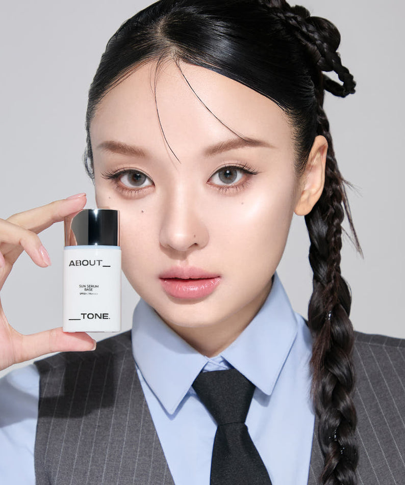 ABOUT TONE Sun Serum Base 30ml (SPF50+, PA++++), femme en tenue pro tenant le flacon, contexte beauté cosmétique