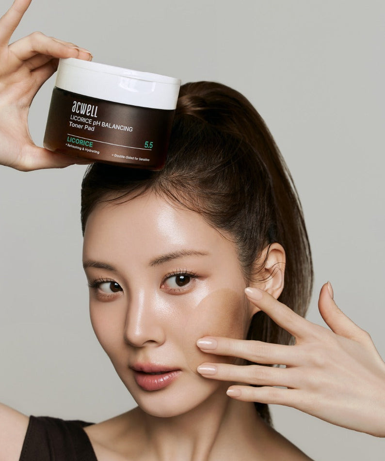 Femme avec pot de ACWELL Licorice pH Balancing Toner Pad 70P devant un fond gris.