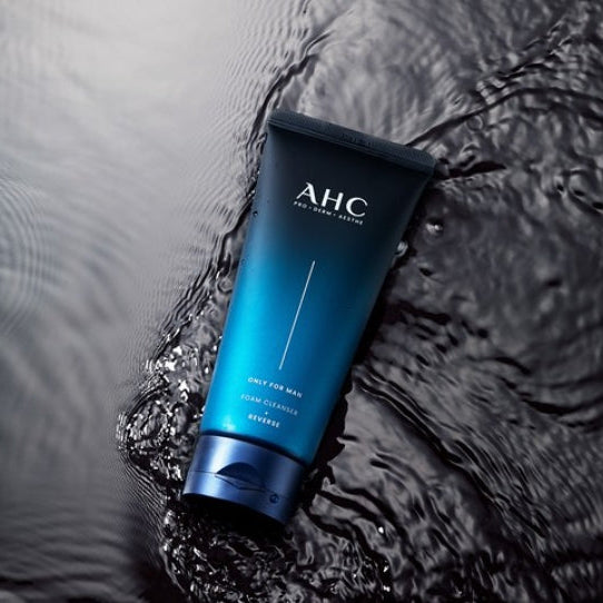 Décris l'image en français : AHC Only For Men Foam Cleanser 140ml de la marque AHC sur tissu humide, flacon bleu.