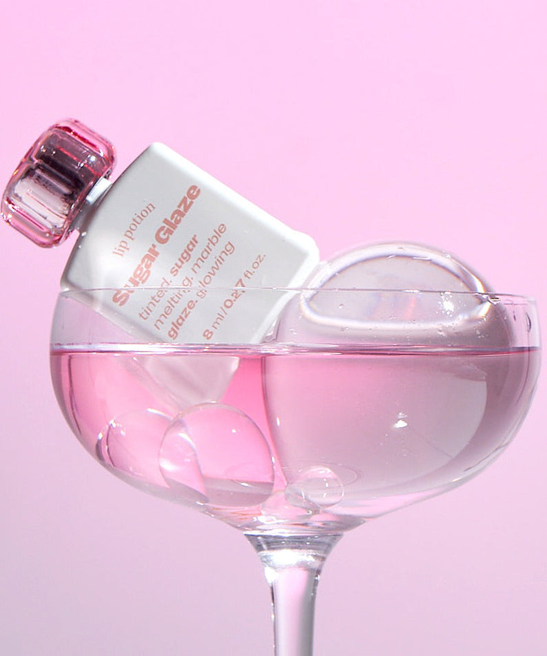 ALTERNATIVE STEREO Lip Potion Sugar Glaze Tint 8ml, produit de maquillage présenté dans un flacon rosé sur fond rose.