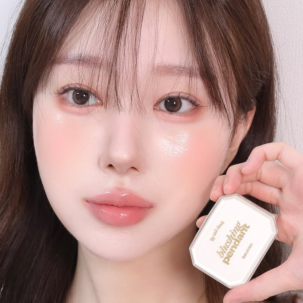 Femme utilisant ALTERNATIVE STEREO Blushing Pendant Lip & Cheeck, maquillage léger et élégant pour lèvres et joues.