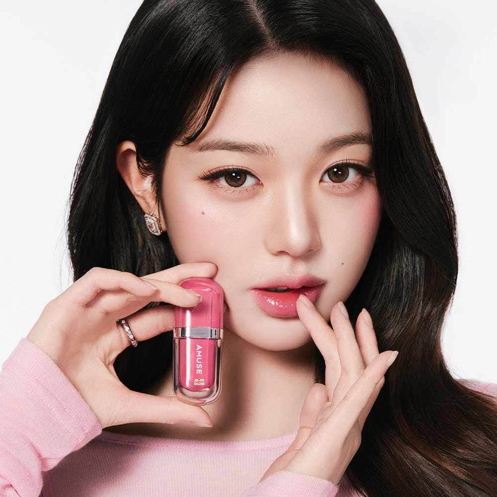AMUSE Jel Fit Gloss : femme maquillée tenant le gloss rose, portrait en studio sur fond clair
