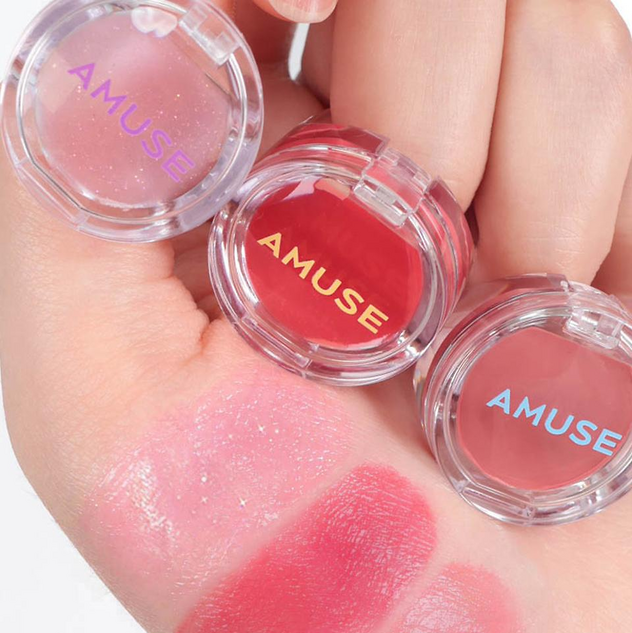 AMUSE Ring Lip Balm Jewelry de la marque AMUSE, photo en gros plan avec plusieurs baumes en forme de bague sur peau.