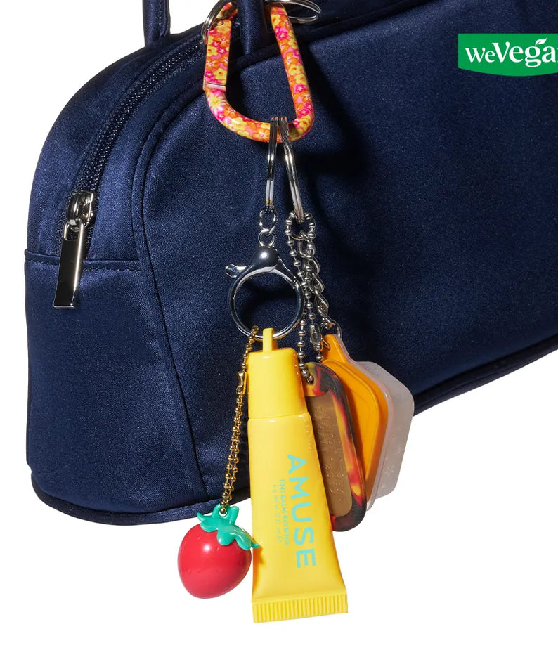 AMUSE TINT BALM KEYRING d’AMUSE en porte-clés, avec mini baume sur sac bleu, fond blanc, style produit.