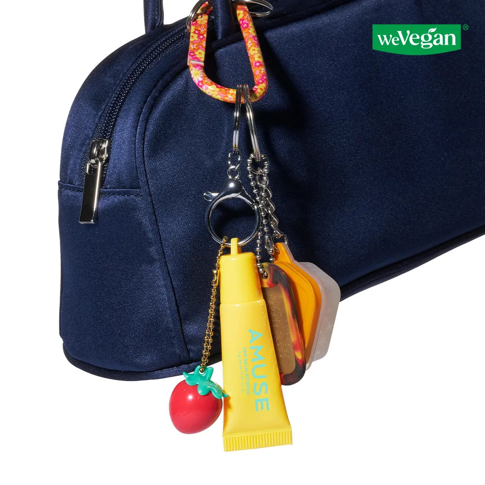 AMUSE TINT BALM KEYRING d’AMUSE en porte-clés, avec mini baume sur sac bleu, fond blanc, style produit.
