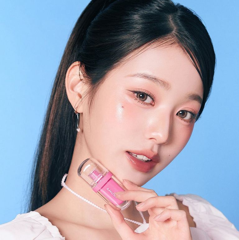 AMUSE Jel-Fit Tint : femme tenant le produit maquillage en gel, gros plan sur peau éclatante fond bleu ciel.