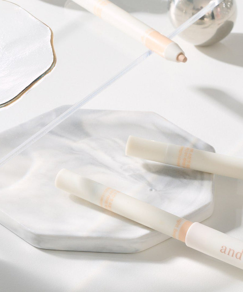 AND:AR Soft Skinfit Dual Concealer Pencil sur un plateau en marbre blanc, produit cosmétique pour un teint parfait.