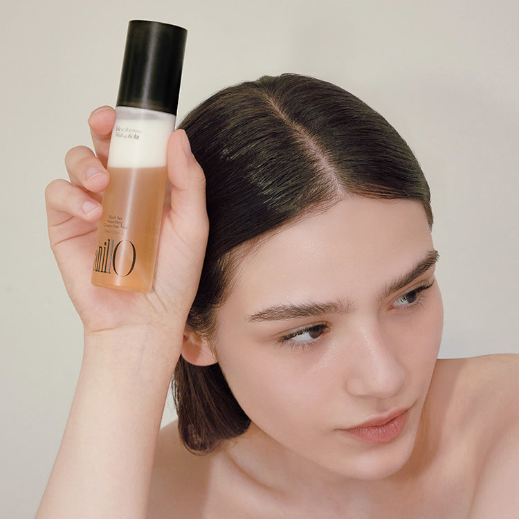 ANILLO Black Tea Nourishing Cream Hair Mist 70ml de la marque ANILLO, flacon tenu près des cheveux d’une femme.