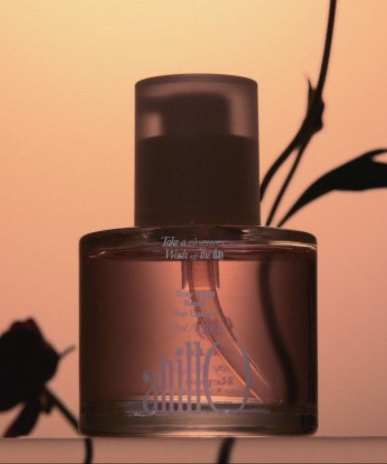 ANILLO Rosy Night Repair Hair Essence 50ml, flacon sur fond beige chaud avec feuilles noires en arrière-plan.