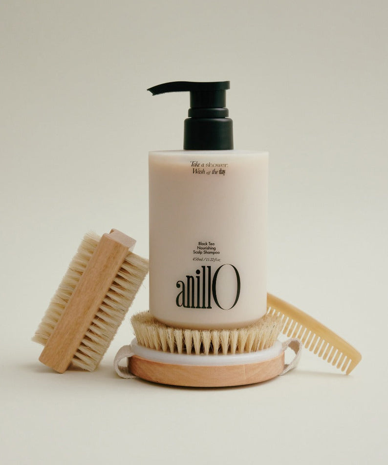 ANILLO Black Tea Nourishing Scalp Shampoo 450ml, flacon noir et blanc avec brosses en bois, sur fond clair.