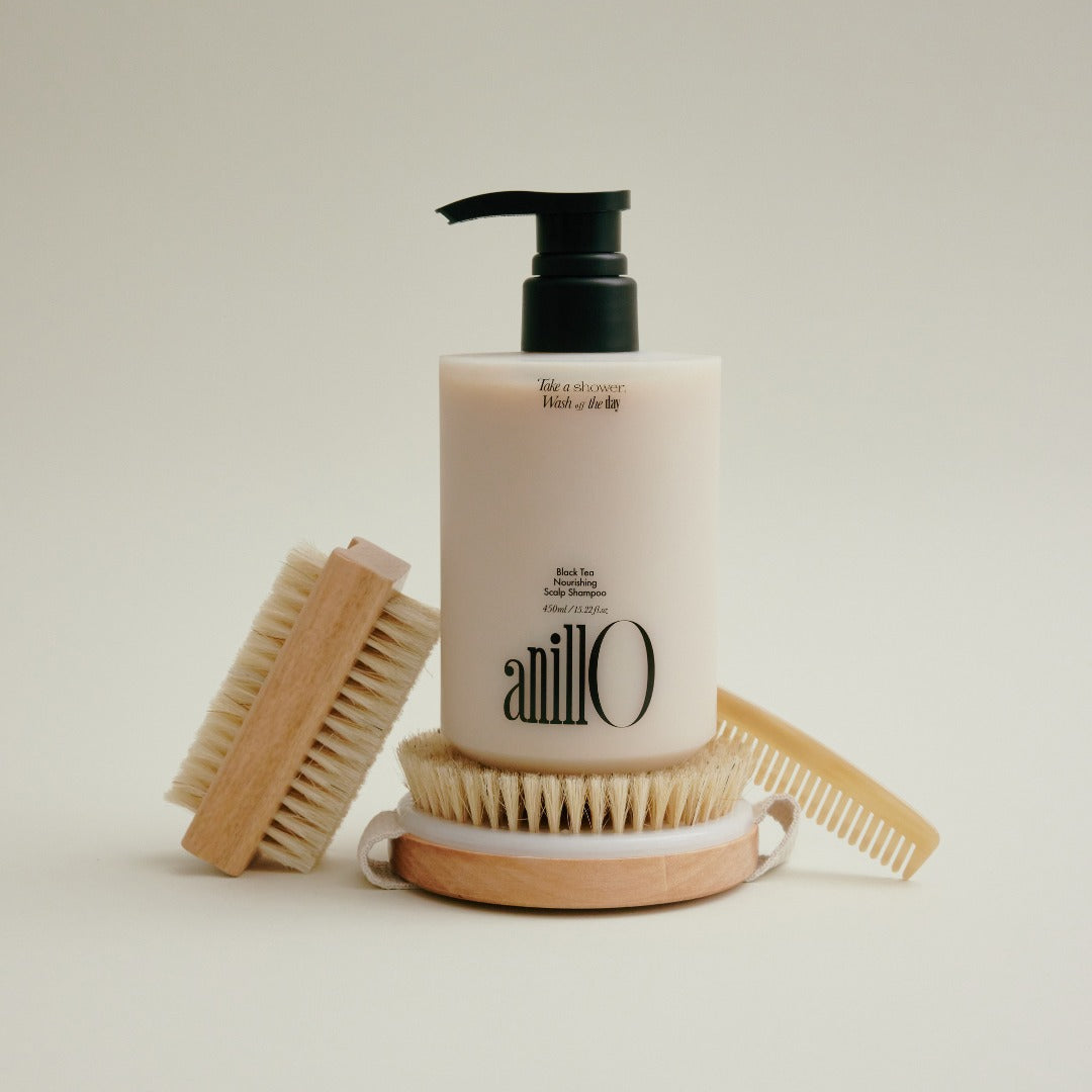 ANILLO Black Tea Nourishing Scalp Shampoo 450ml, flacon noir et blanc avec brosses en bois, sur fond clair.