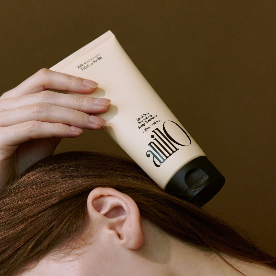 ANILLO Black Tea Nourishing Scalp Treatment 150ml sur une tête, mains appliquant le produit, contexte beauté.