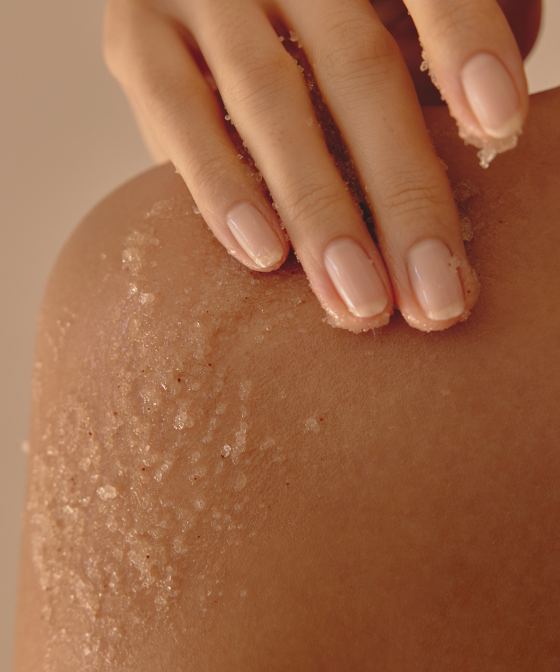 ANILLO Fig Whisky Body Scrub 240g, exfoliation sur peau avec mains, texture granuleuse, ambiance spa visuel
