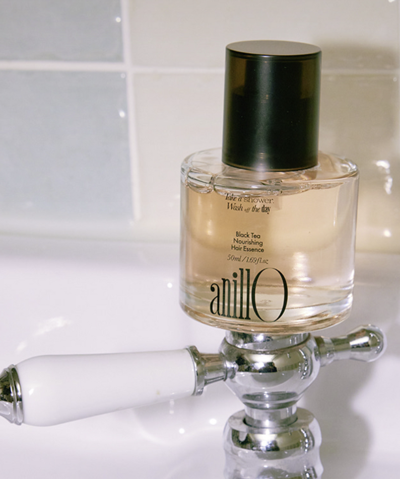 ANILLO Black Tea Nourishing Hair Essence 50ml : flacon sur support chromé, salle de bain lumineuse, esthétique premium.