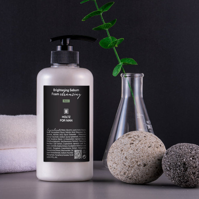 ANNA HOLTZ For Men Brightening Sebum Foam Cleansing 500ml : flacon sur fond noir, accessoires spa et feuilles vertes