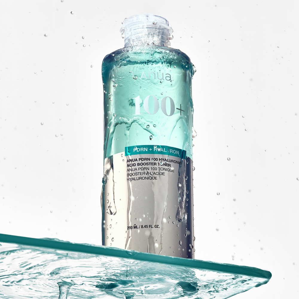 ANUA PDRN 100 Hyaluronic Acid Booster Toner 250ml, bouteille sur fond blanc avec éclaboussures d’eau, style skincare.
