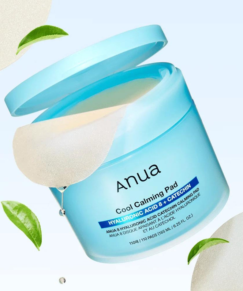 Décris l'image en français : ANUA 8 Hyaluronic Acid Catechin Calming Pads 110 Pads, marque ANUA, pot bleu, feuilles vertes.