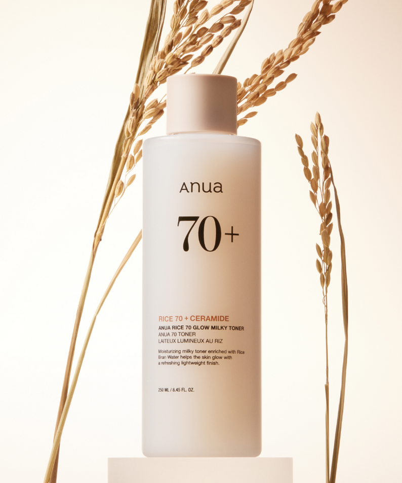 Décris l'image en français : ANUA Rice 70 + Ceramide Glow Milky Toner 250ml, bouteille blanche ANUA sur fond clair, avec épis de blé.