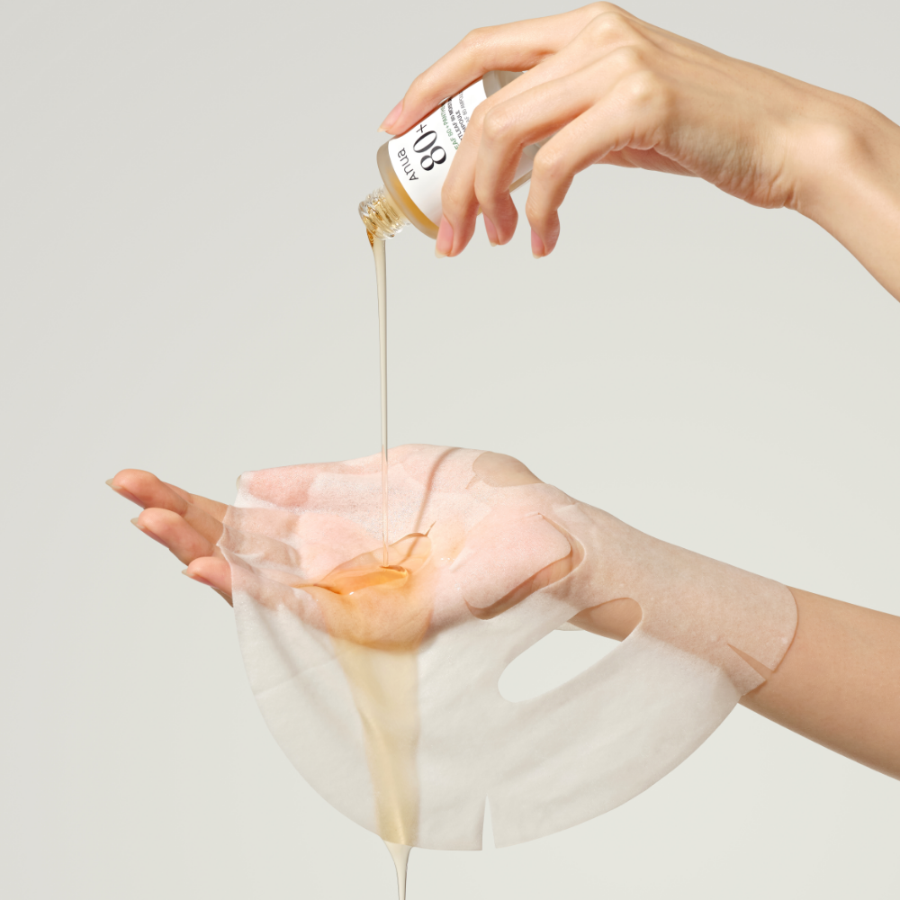 ANUA Heartleaf 80 + Panthenol Moisture Soothing Ampoule Mask, main appliquant une ampoule sur un masque en tissu, visage.