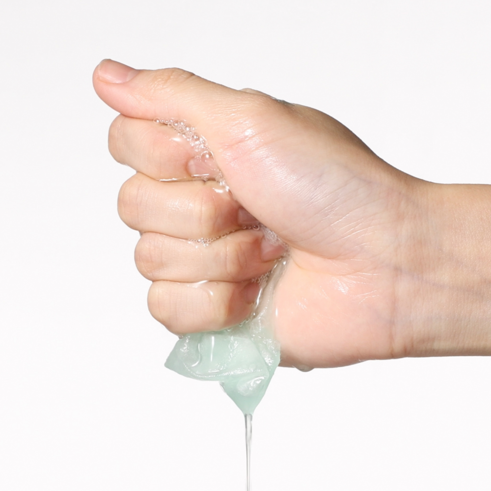 ANUA PDRN Hyaluronic Acid Capsule 100 Serum Mask de la marque ANUA, main applique un sérum fluide sur peau, fond blanc