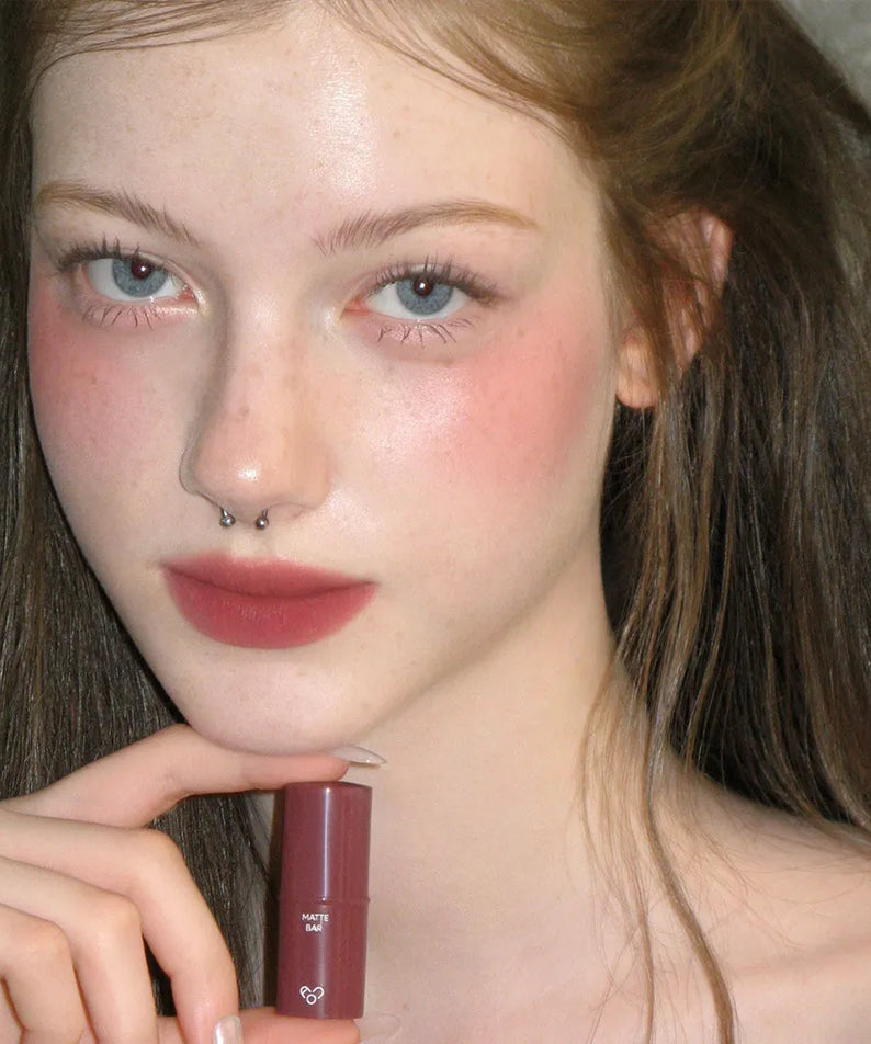 AOU Matte Bar par la marque AOU, rouge à lèvres mat, porté sur lèvres, portrait maquillage en fond sombre.