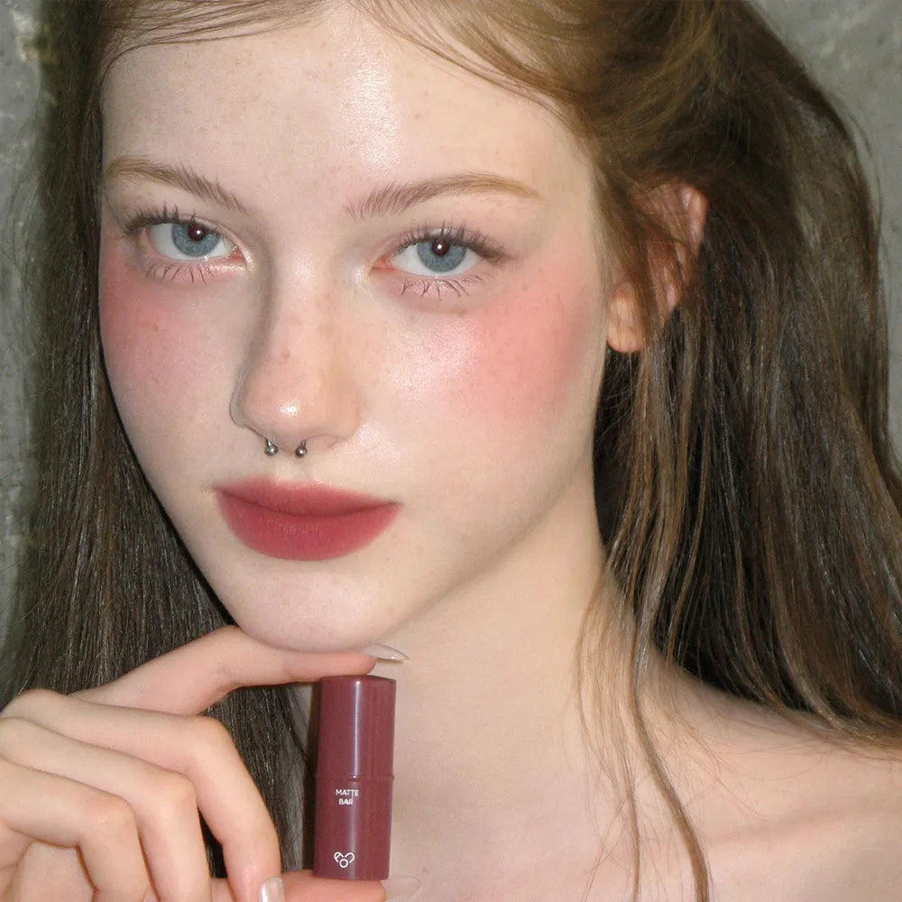 AOU Matte Bar par la marque AOU, rouge à lèvres mat, porté sur lèvres, portrait maquillage en fond sombre.