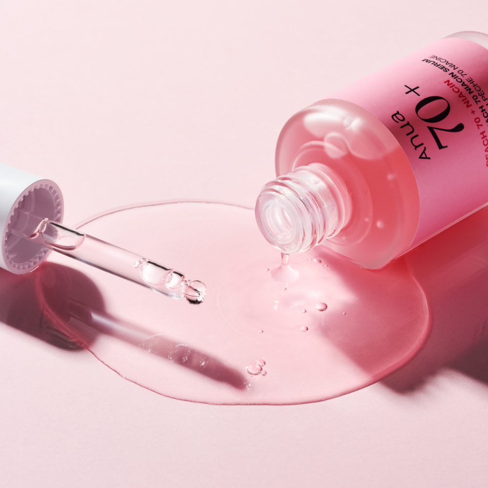 ANUA Peach 70 + Niacin Serum 30ml de la marque ANUA, sur fond rose, sérum coulant depuis le flacon.